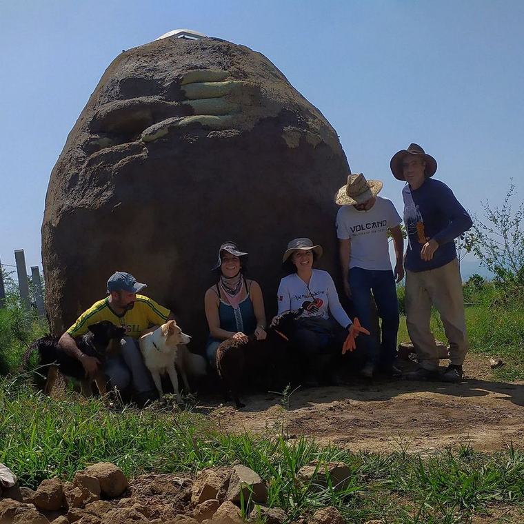 Grupo de colaboradores y sus perros frente a una construcción de bahareque terminada